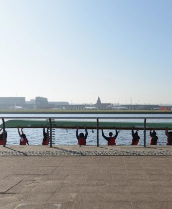 Scene of waterfront with people lifting a boat together