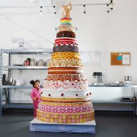 Giant cake with many layers and an astonished child looking up at it