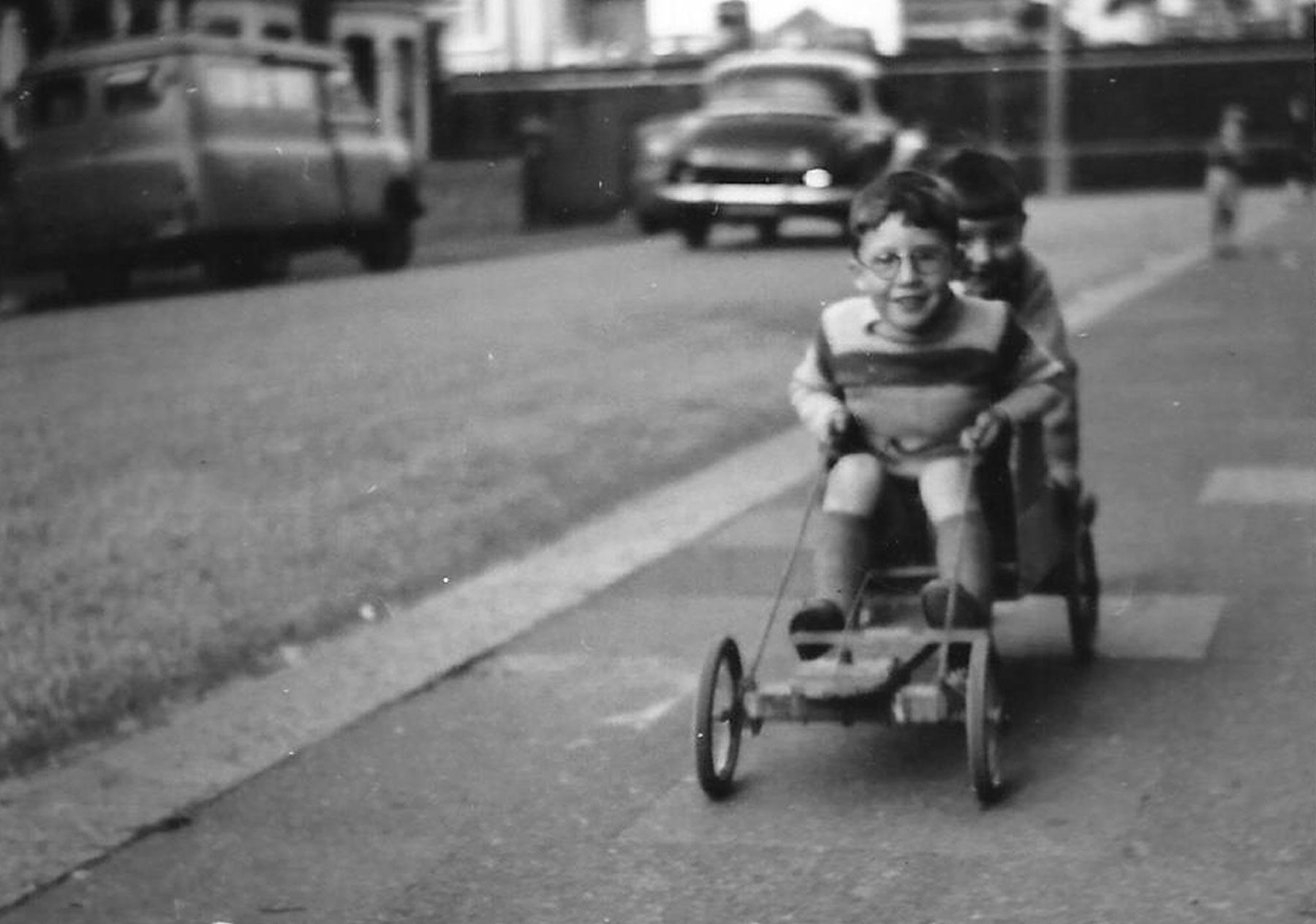 Old photo of children riding a go cart in the street