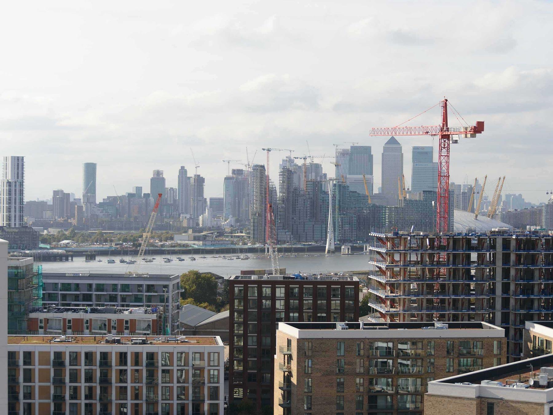 Modern day scene of buildings, cranes and the Canary Wharf skyline in the distance