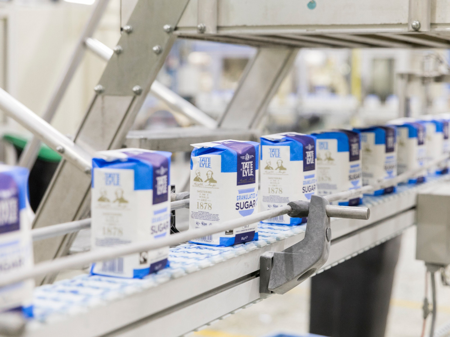 Packages of Tate & Lyle sugar on a conveyor belt in a factory