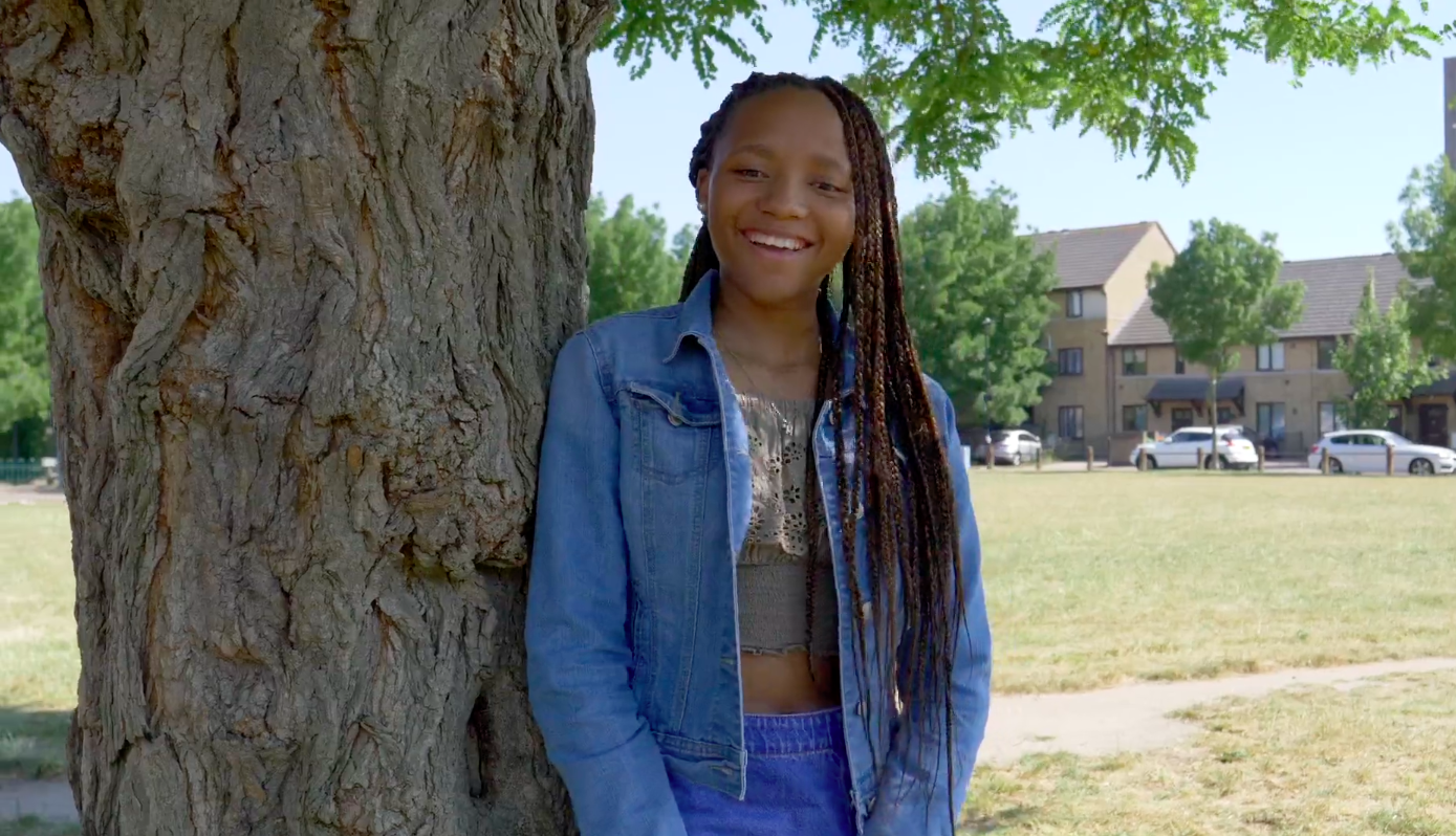 Girl standing next to tree