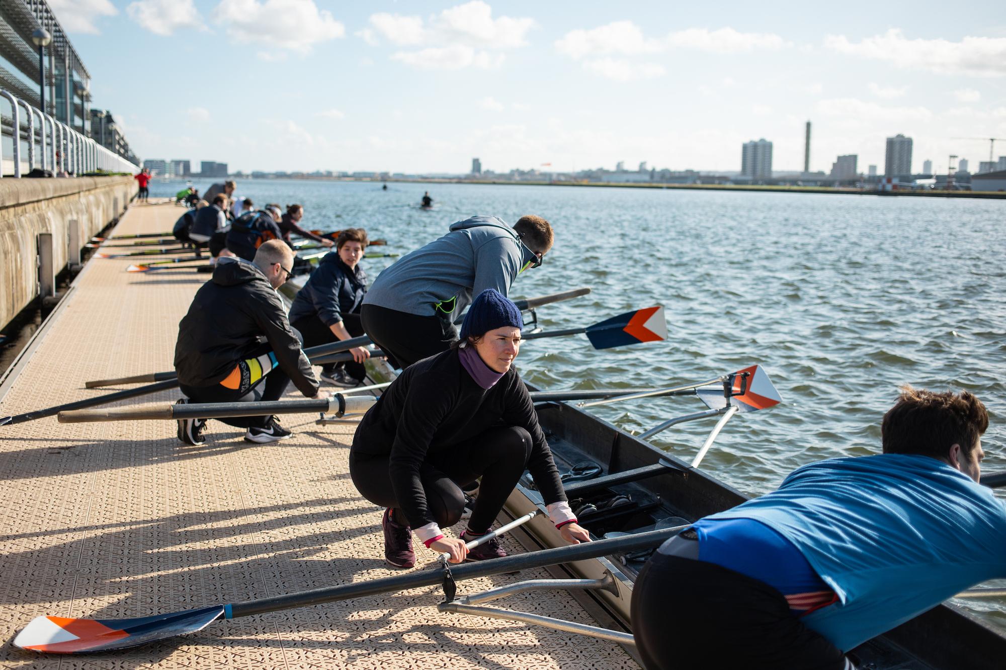 rowers crouched down to prepare the boat before getting onto the water