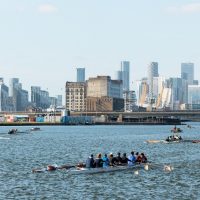 rowers on the water with all of canary wharf in the background