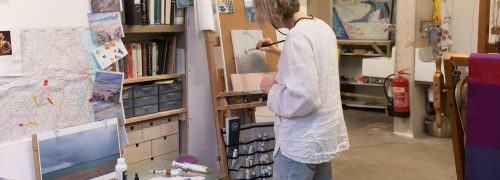 Artist in a studio painting at an easel