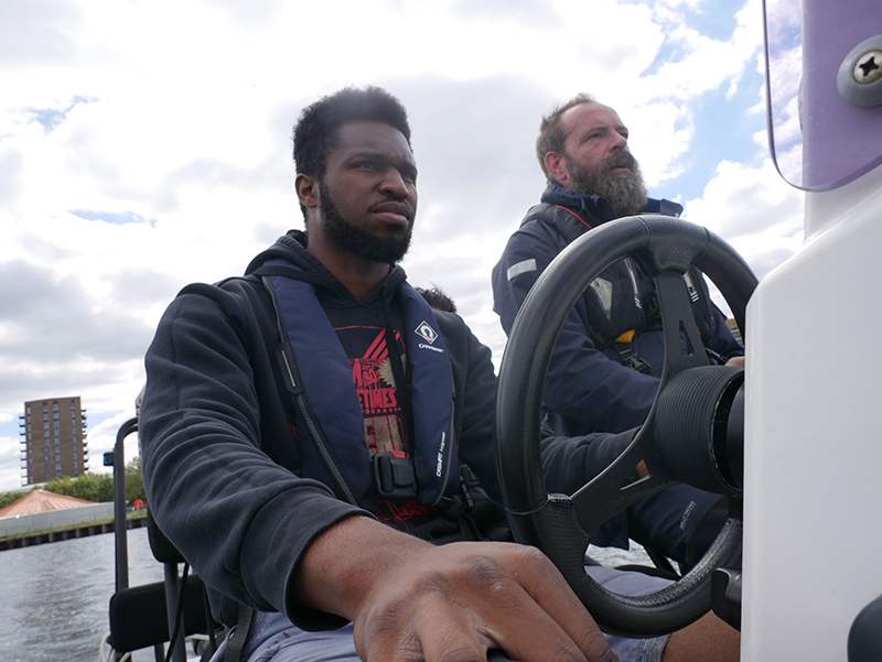 Tyrone Ferguson steering a boat in the Royal Docks