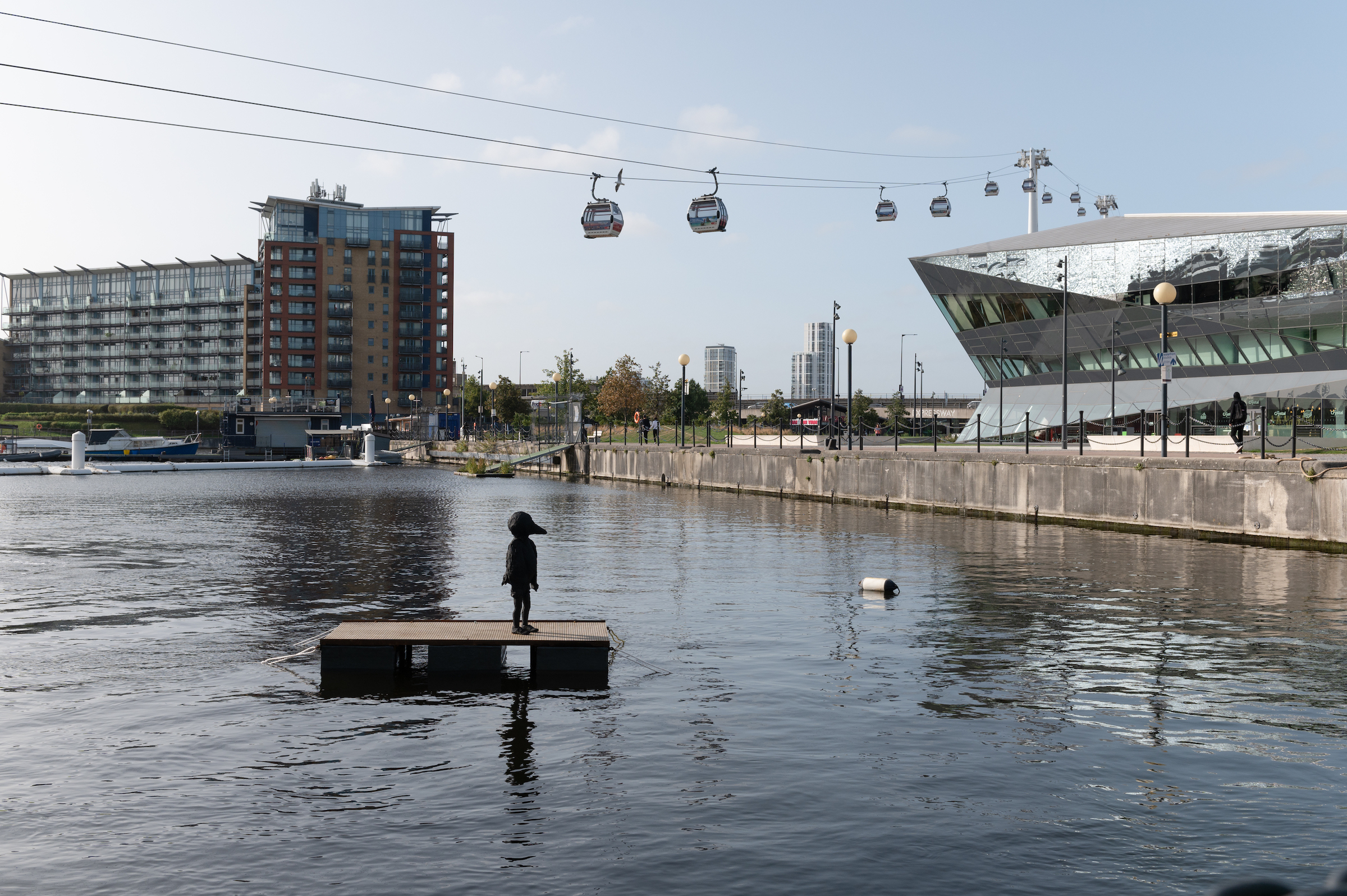 Sculpture of child in bird costume floating on a raft in the dock