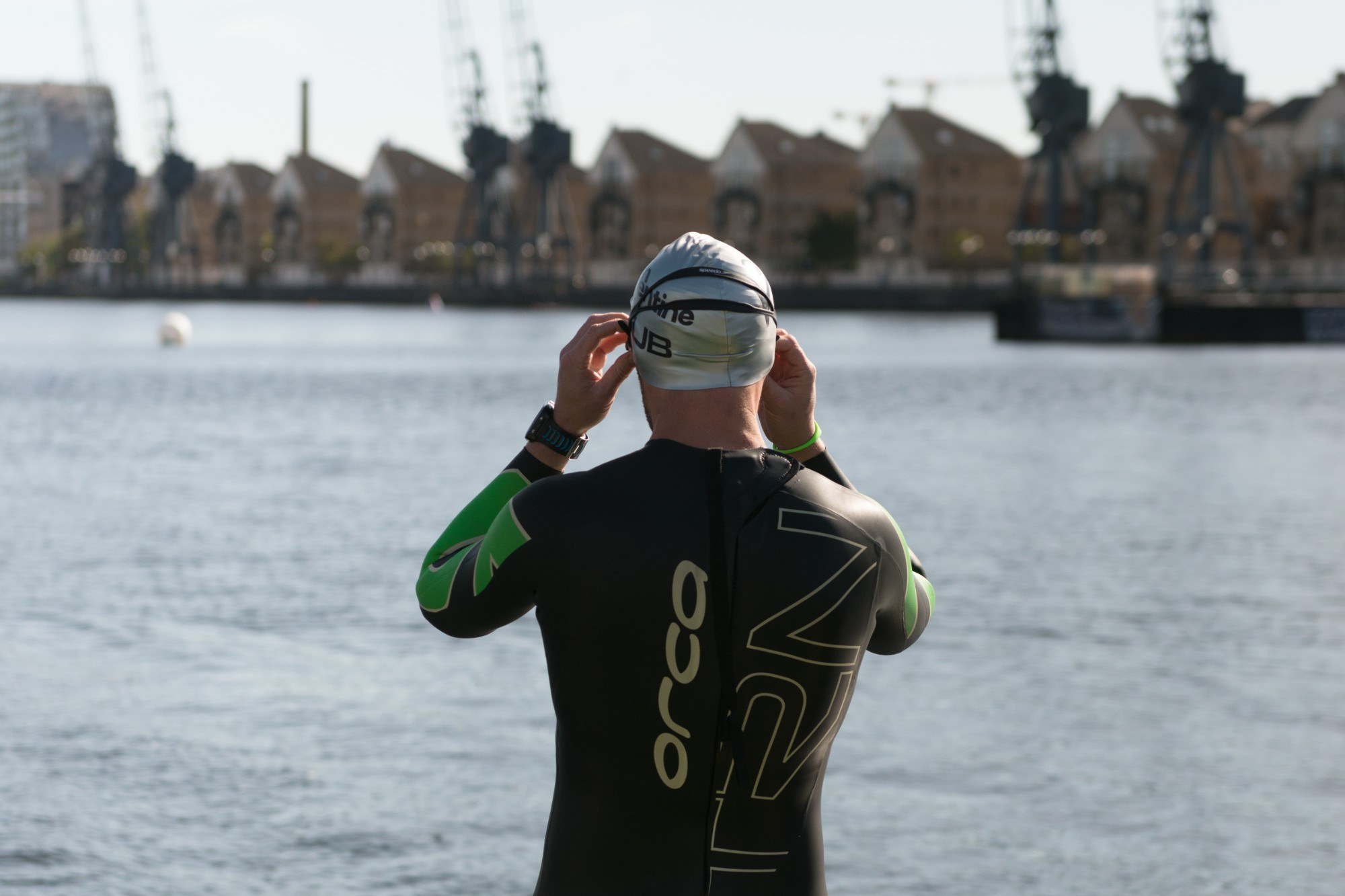 A man in a wetsuit looking over the Royal Docks