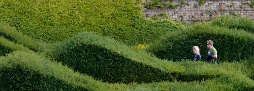 The rolling hedges of thames barrier park with two people walking