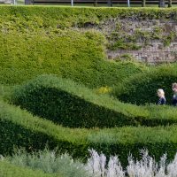 The rolling hedges of thames barrier park with two people walking