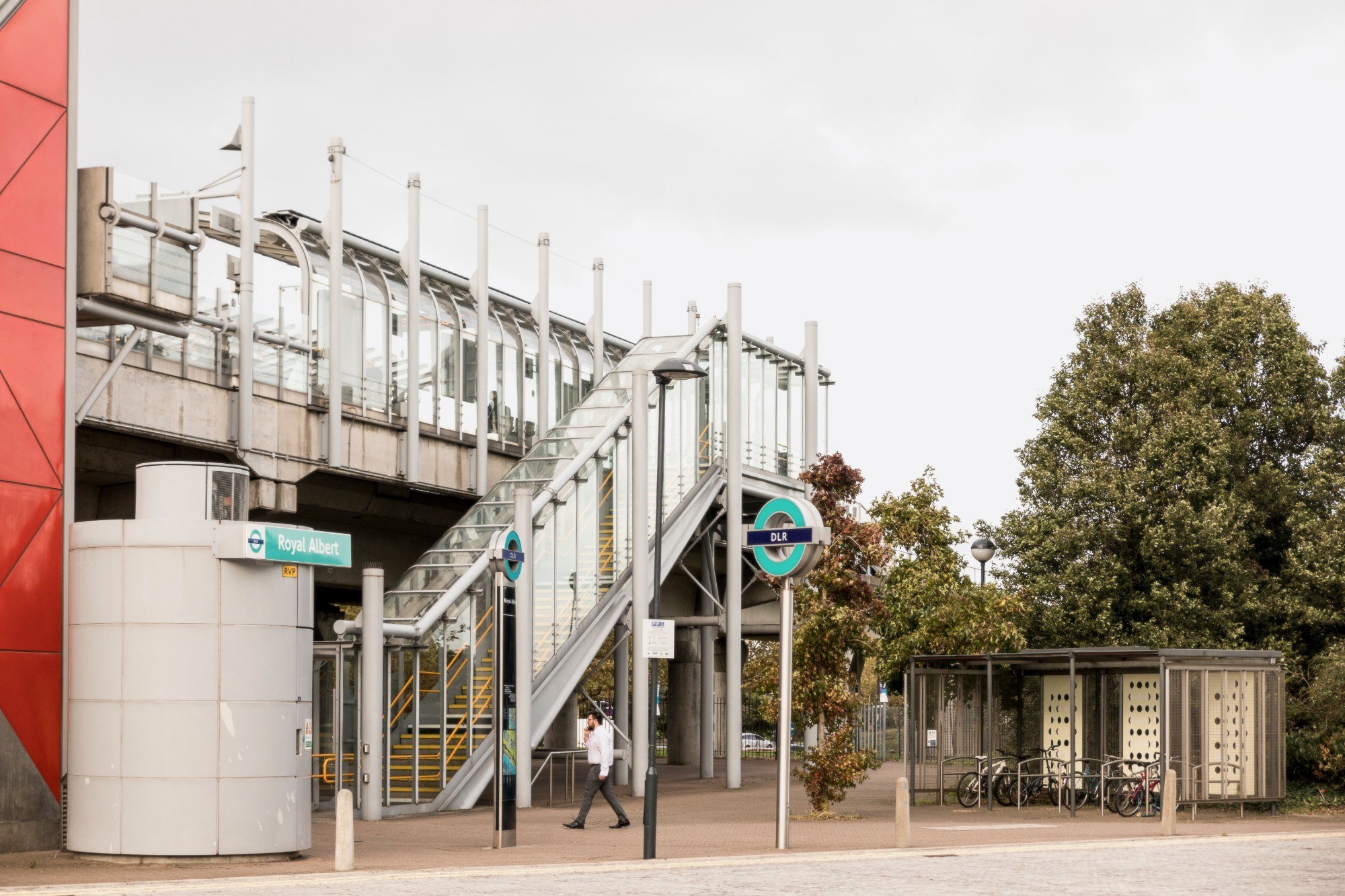 the exterior of royal albert DLR station with the stairs, roundel, and red tower