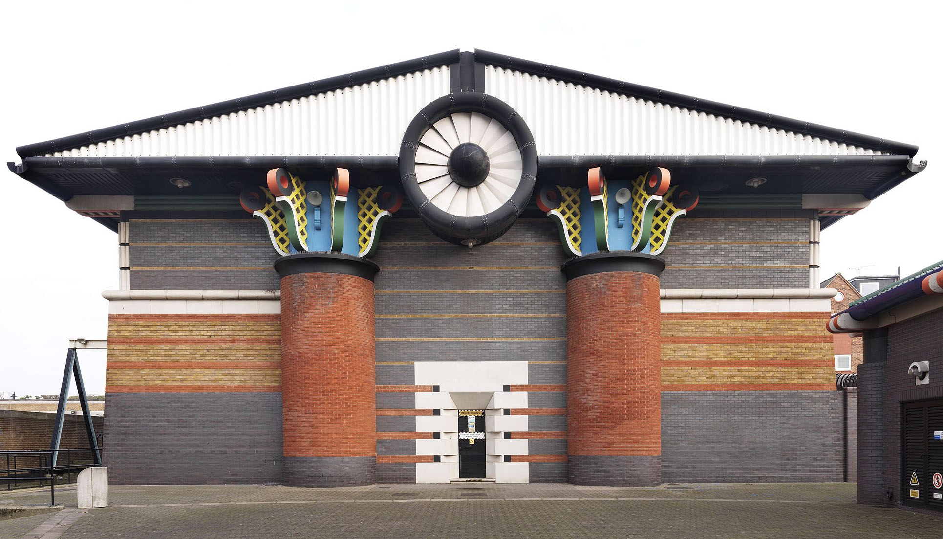 the egyptian inspired postmodern design of the isle of dogs pumping station, with outlandish yellow, blue and red columns plus red, yellow and brown brick