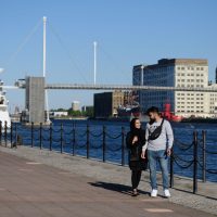 Two people walking along the Royal Docks with Millennium Mills in the background