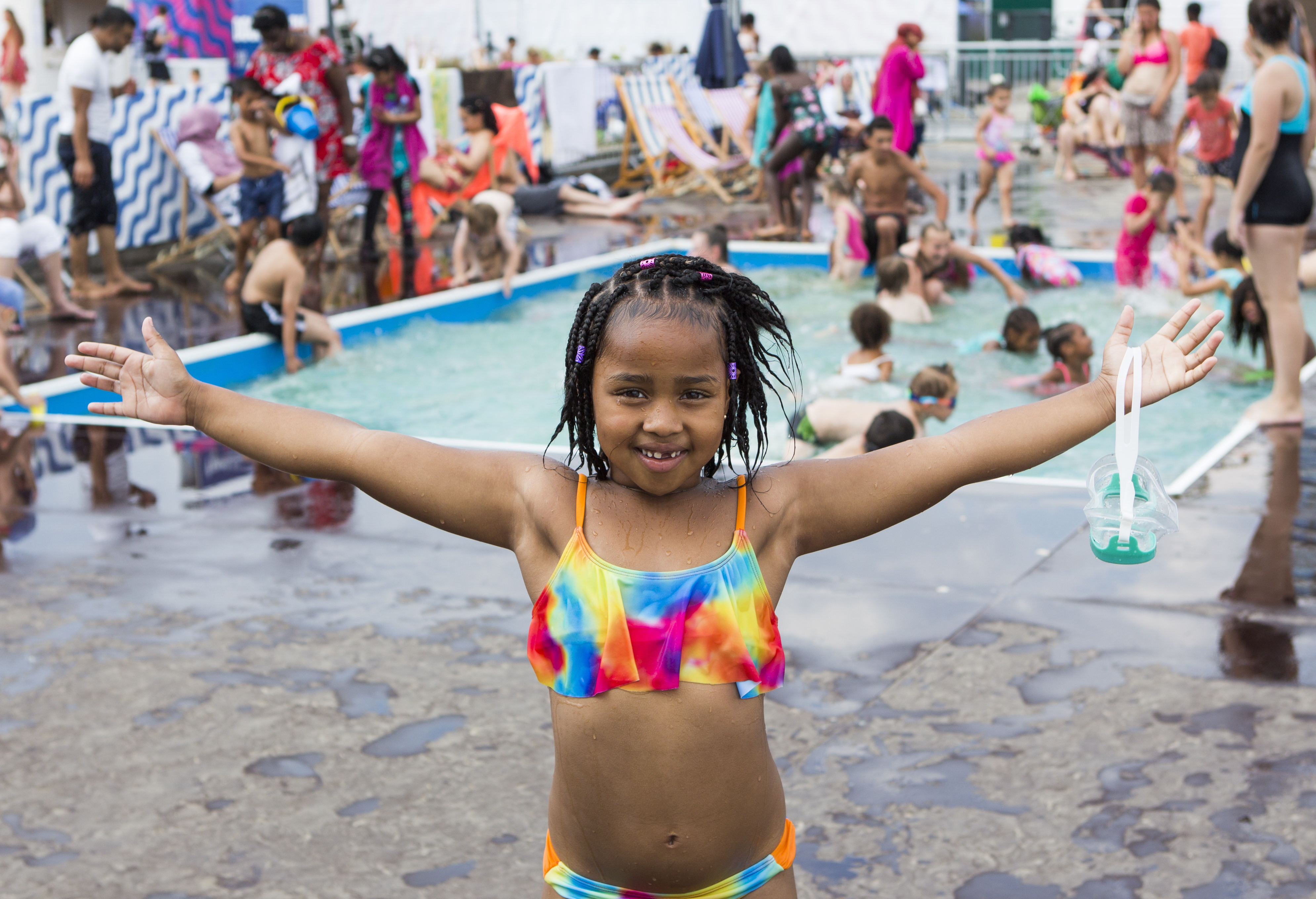 A child at the docks beach pool with a crowd of people in the background