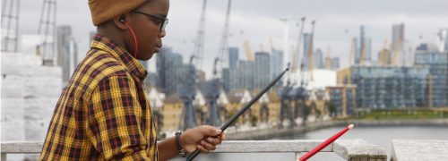 Child using drum sticks on railing at the Royal Docks