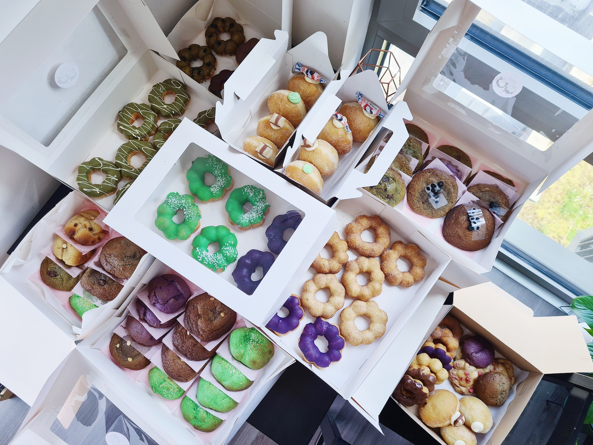 Many boxes of colourful donuts and baked goods