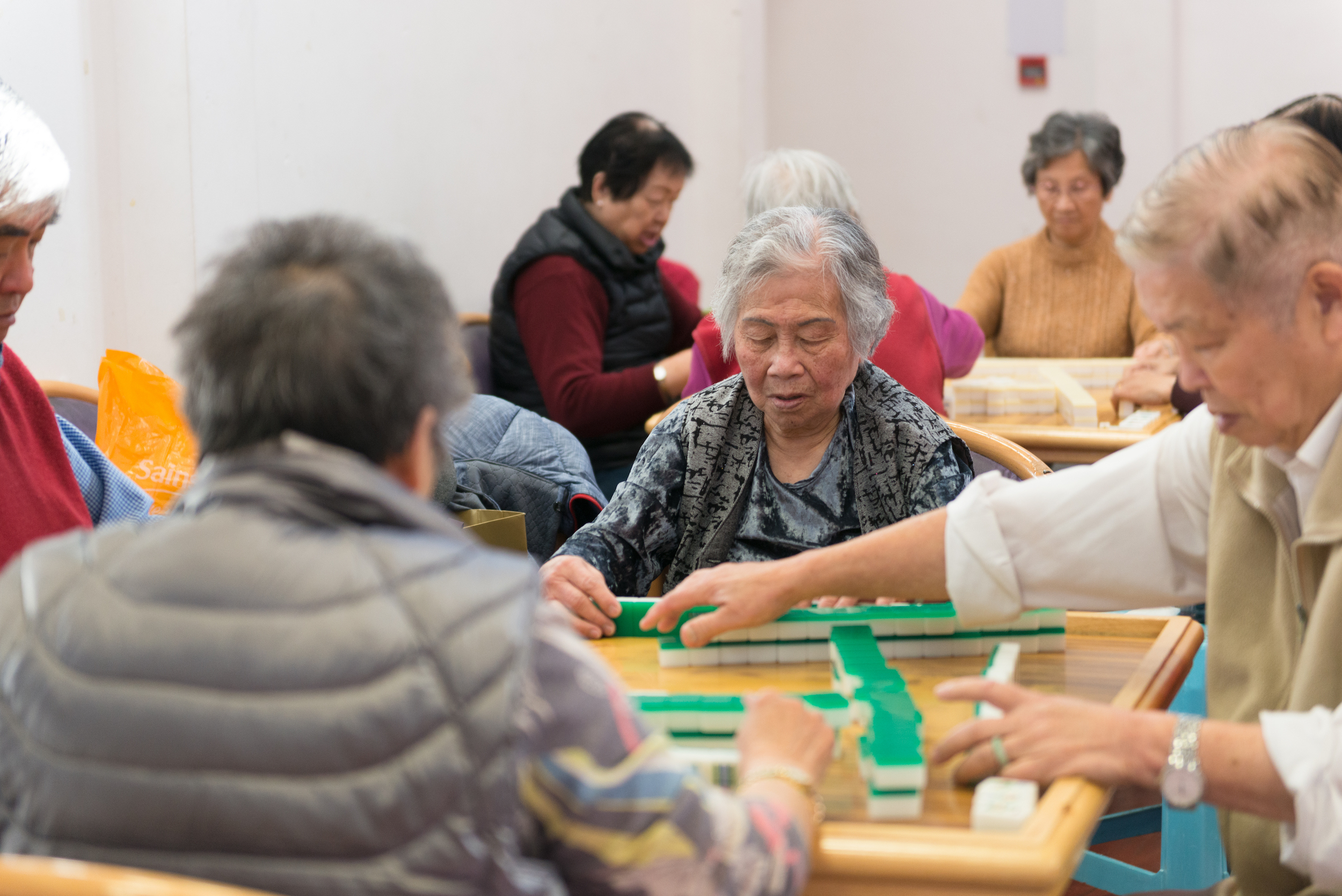 Scene of 8 people playing a table top tile game in groups of four