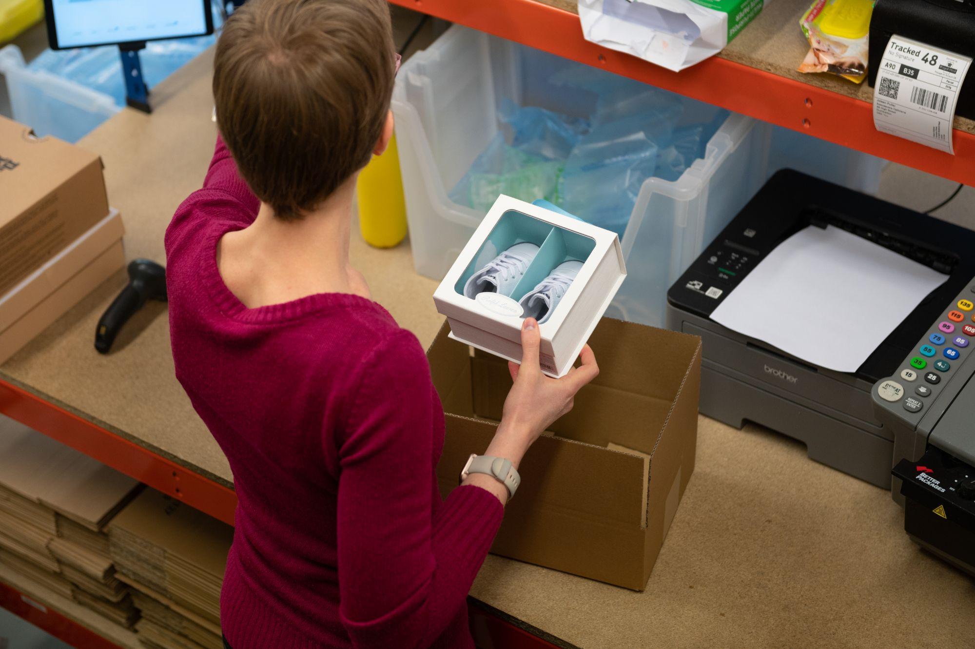 A woman packing a pair of baby shoes