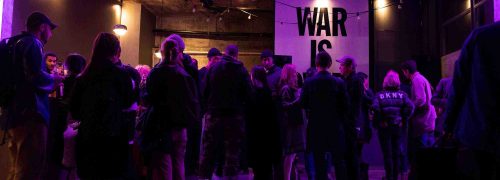 Crowd of people talking a groups, in room with purple lighting