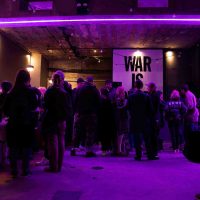 Crowd of people talking a groups, in room with purple lighting