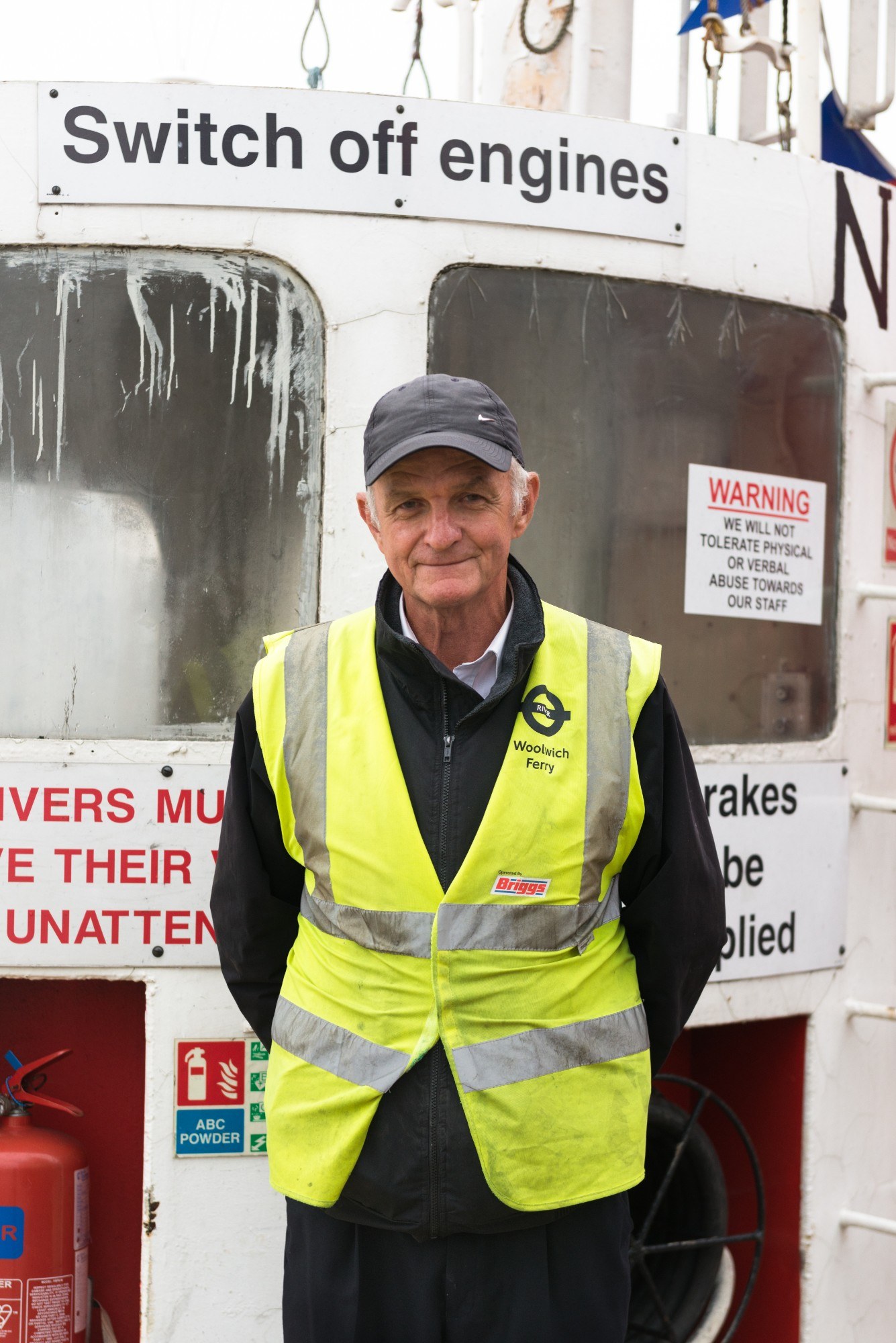 Portrait of ferry operator, with sign saying "switch off engines"