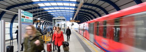 A DLR station platform with a departing DLR train.