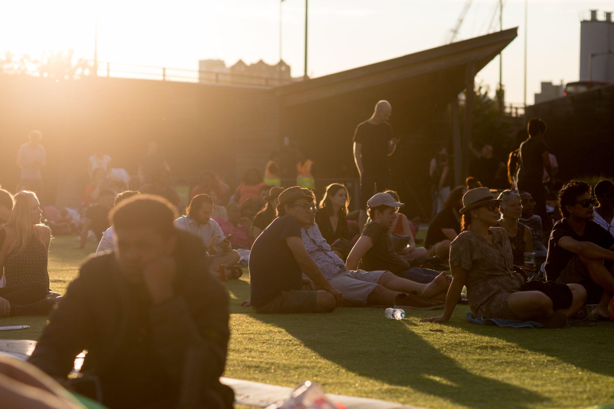 A crowd of people sat on the grass outside The Crystal building