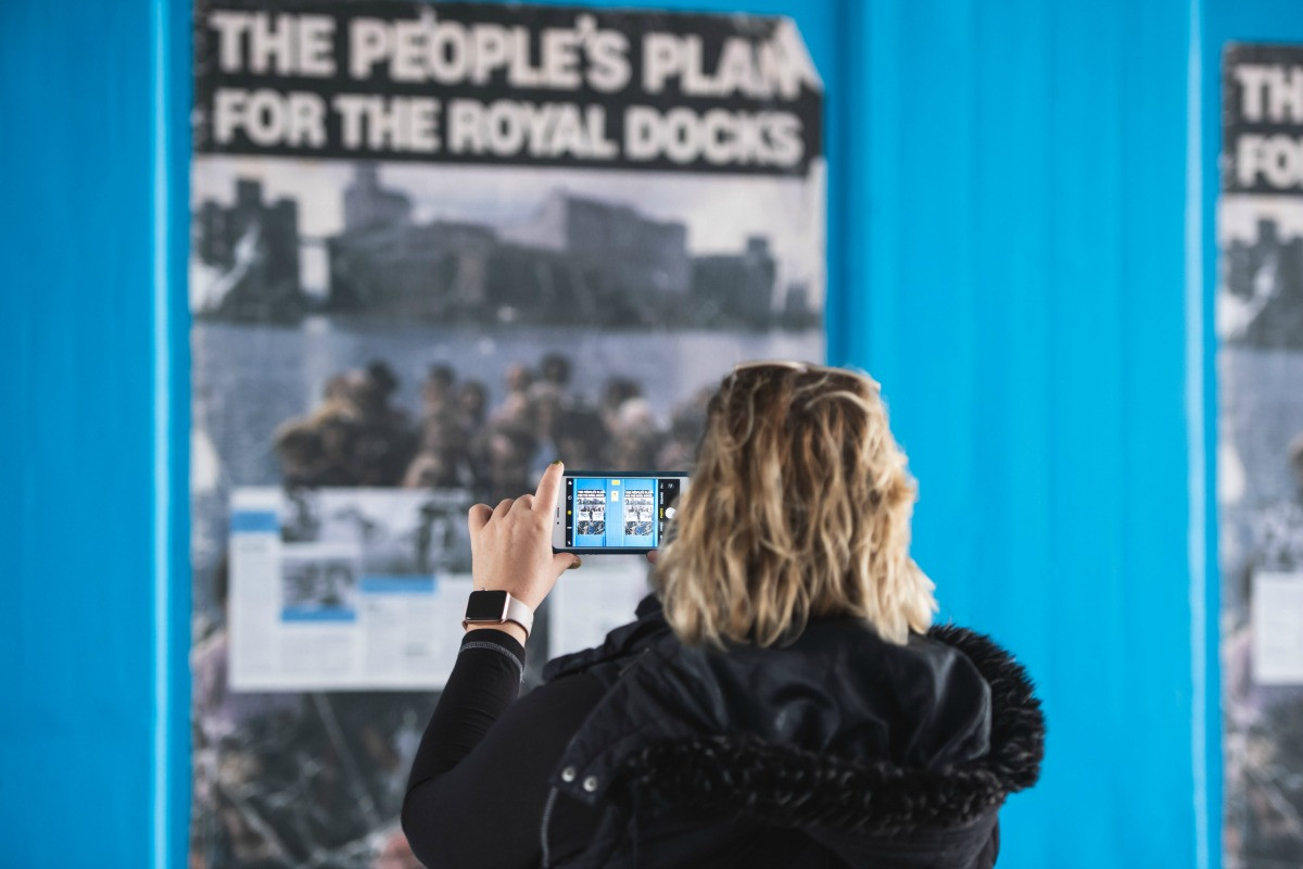 A woman taking a photo of The People's Plan for the Royal Docks
