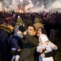 A couple with children taking a selfie in front of a large crowd