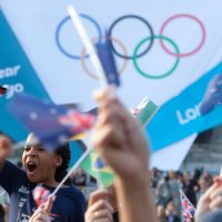 A young girl waves a flag in the crowd before the Olympic rings