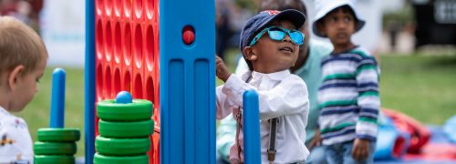 A boy in sunglasses playing with colourful toys