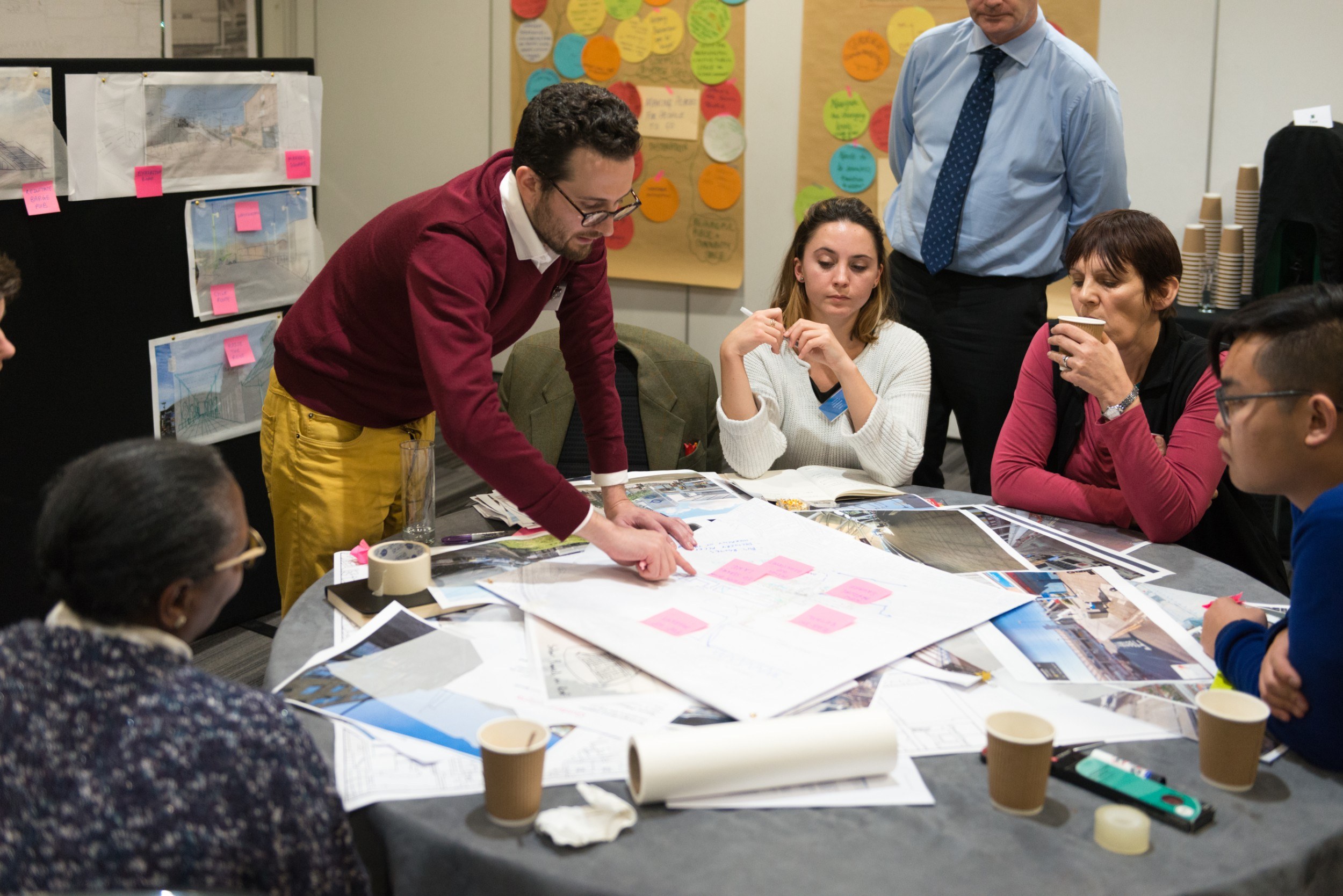 Group of people around a table poring over large pieces of paper