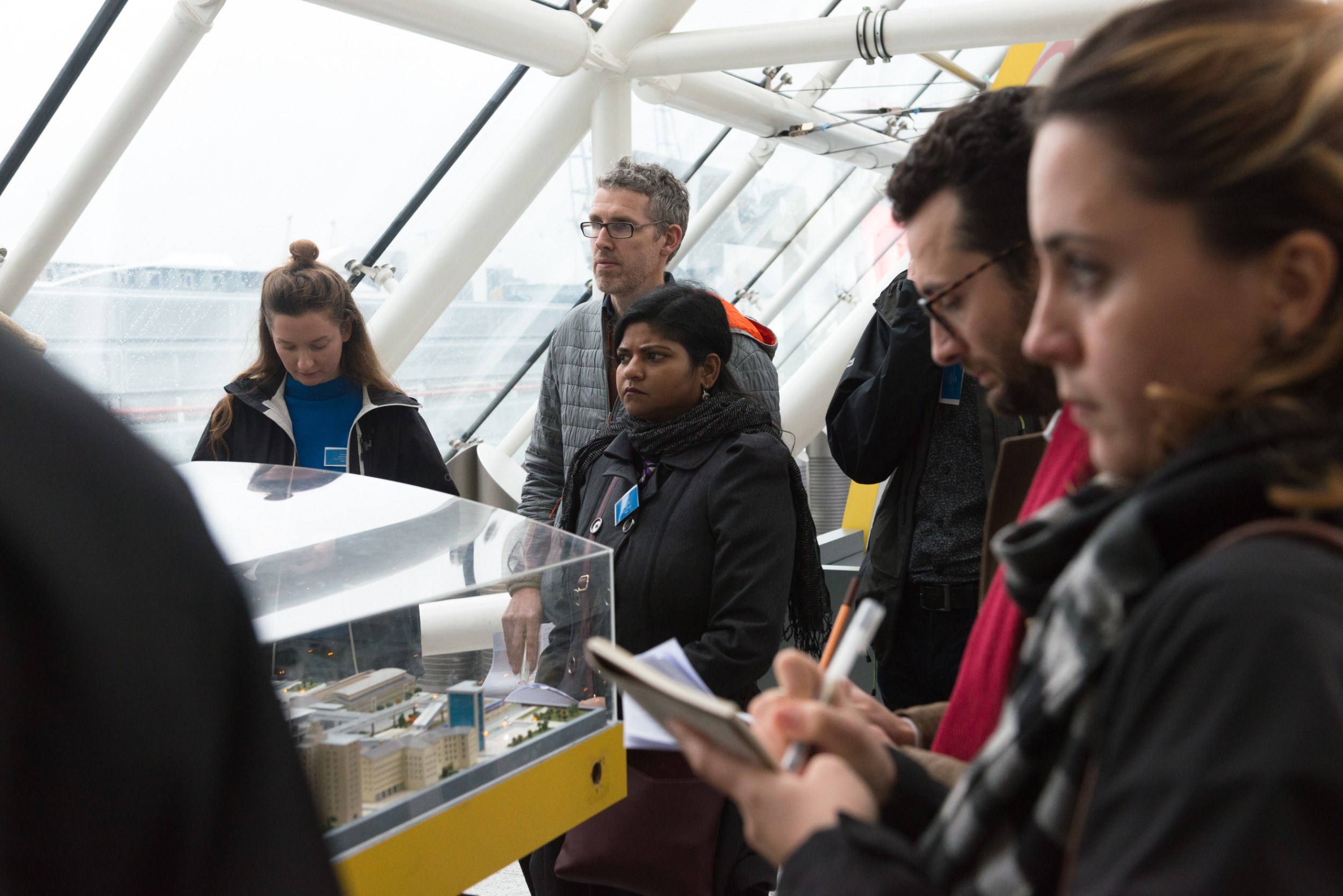 People standing around making notes near an architectural model