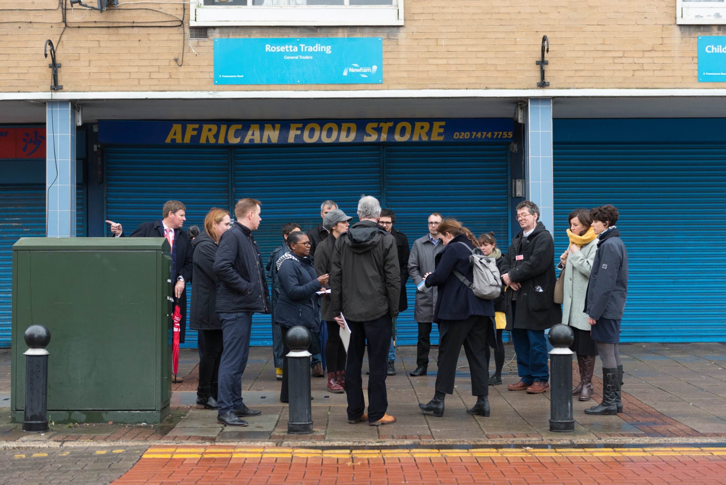 Group of people standing outside a shuttered shopfront