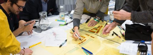 Six people around a table writing out plans