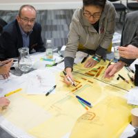 Six people around a table writing out plans