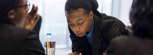 A child writing on a diagram in the centre of a round table