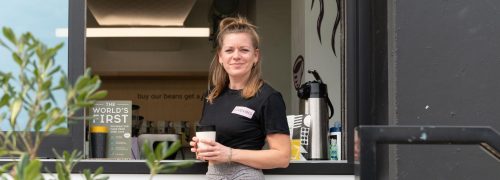 Woman holding coffee outside coffee stall