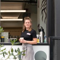 Woman holding coffee outside coffee stall