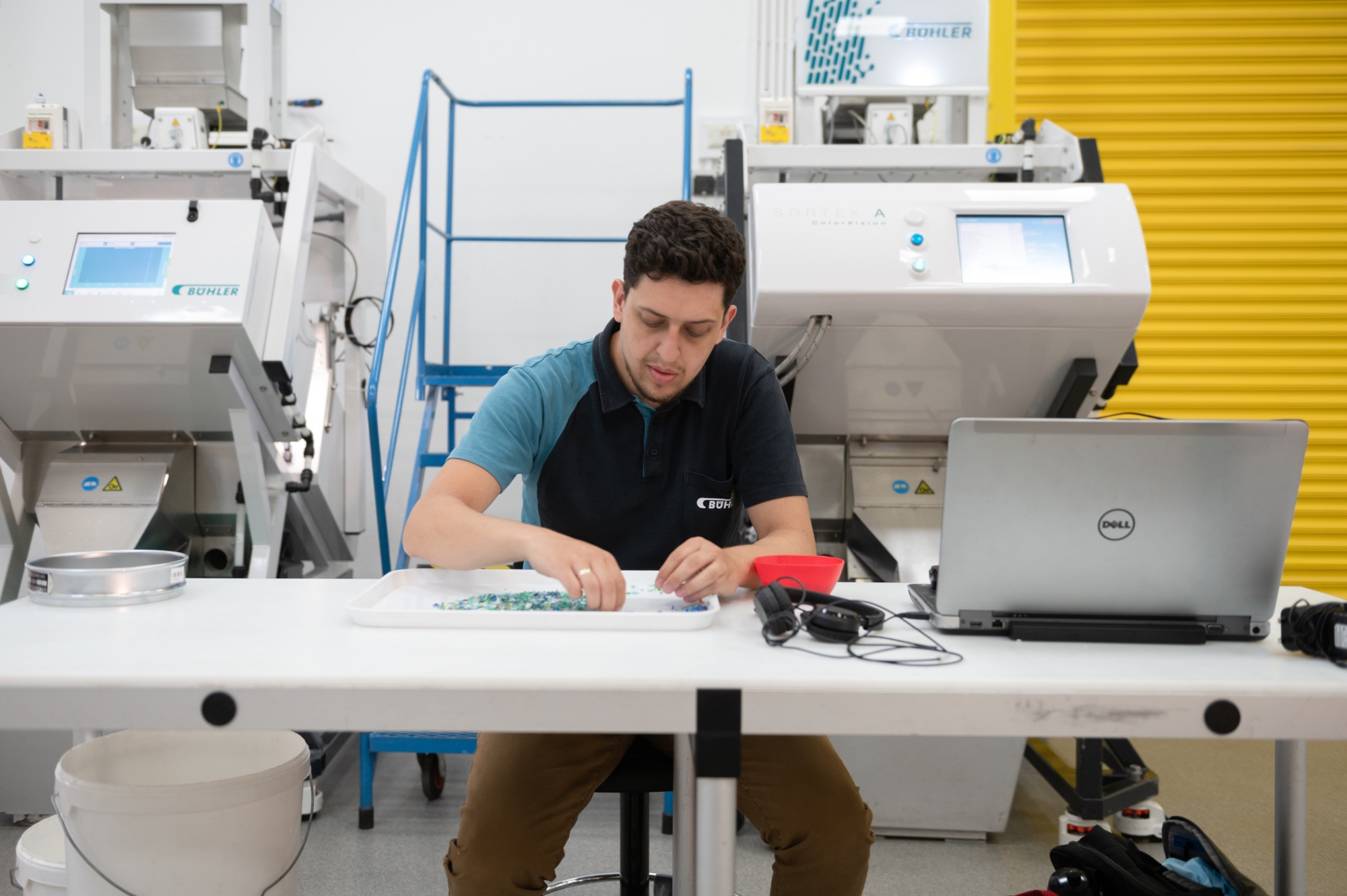 Buhler in the Royal Docks, man sorting tiny pieces of plastic at a desk