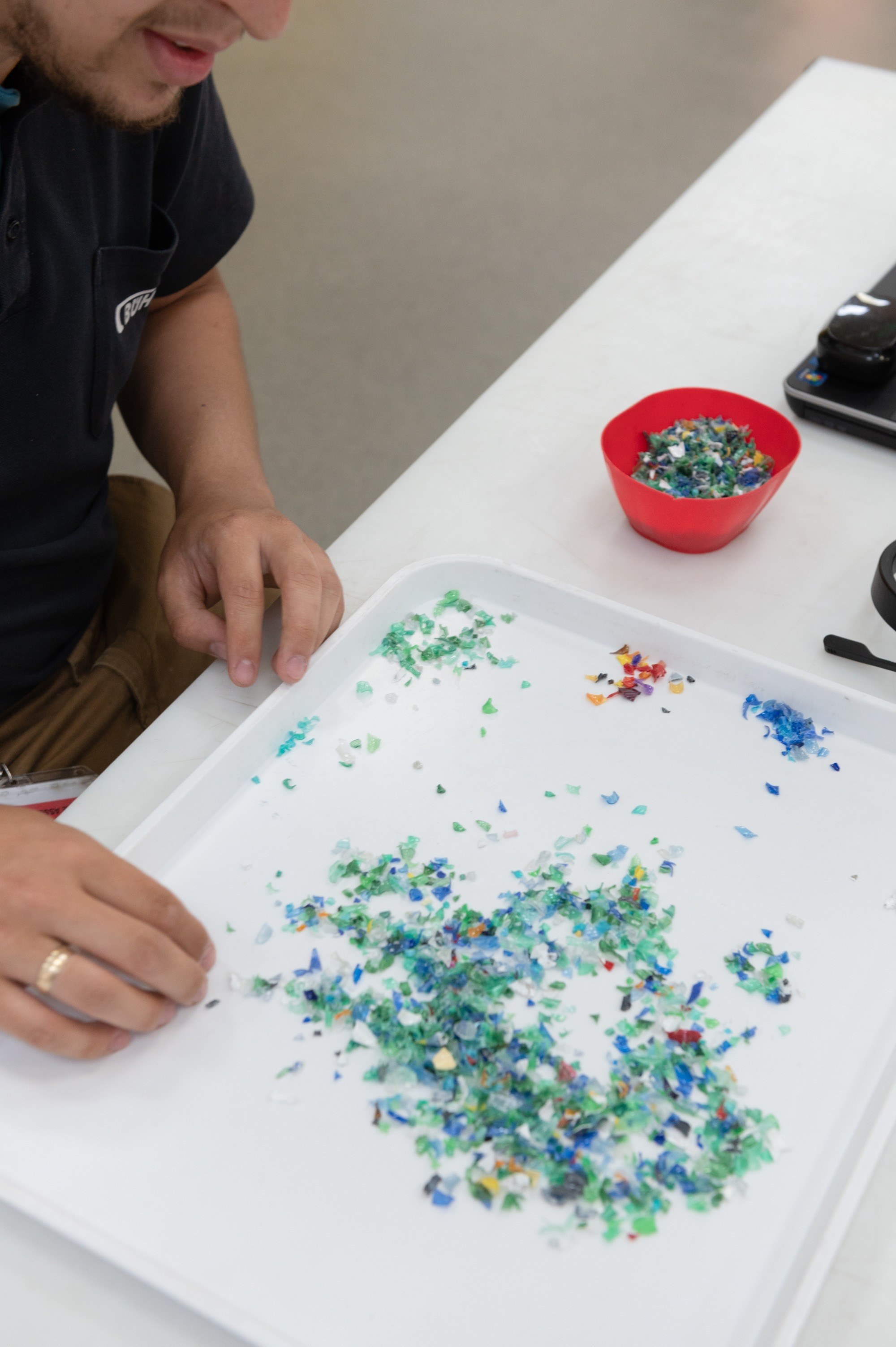 Buhler in the Royal Docks, man sorting tiny pieces of plastic at a desk