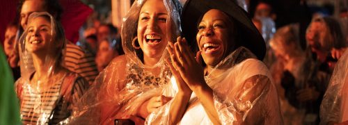 Women in rain coats enjoying an outdoor nighttime show