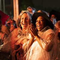 Women in rain coats enjoying an outdoor nighttime show