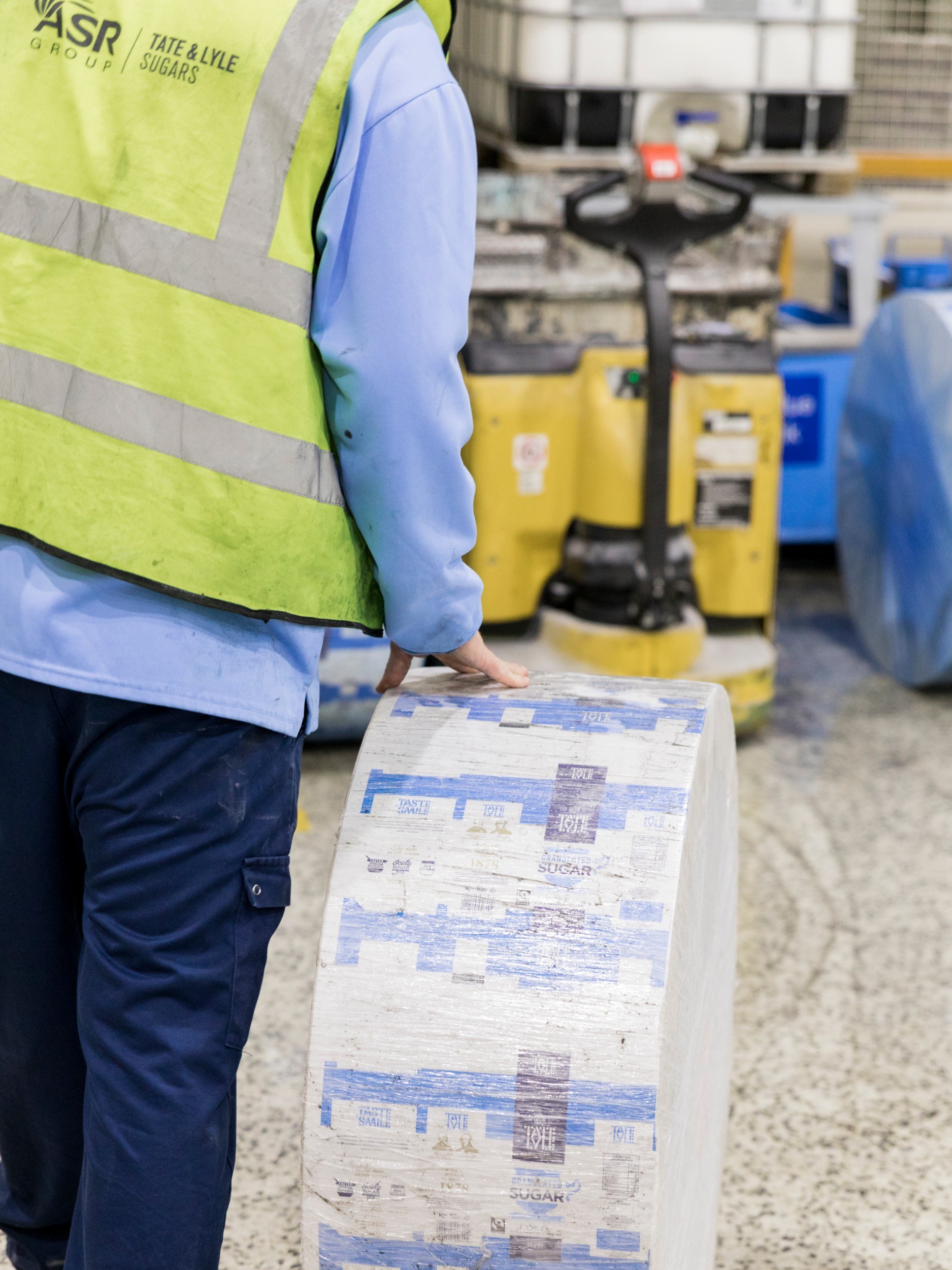 Man rolling stack of sugar bags along the floor