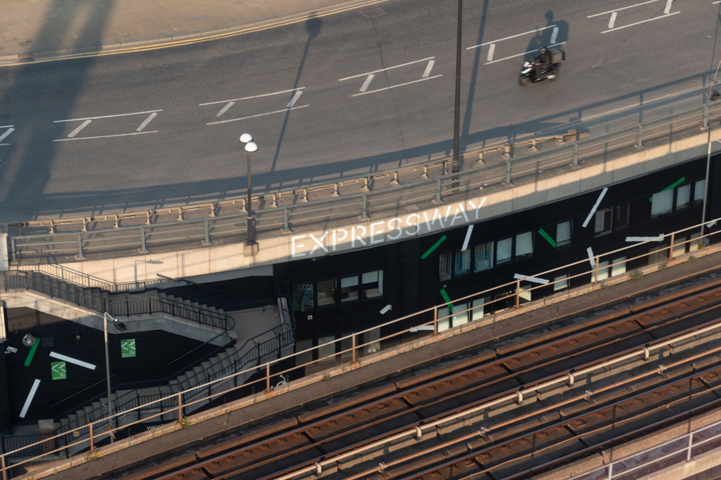 Expressway entrance seen from above, with road and rail tracks