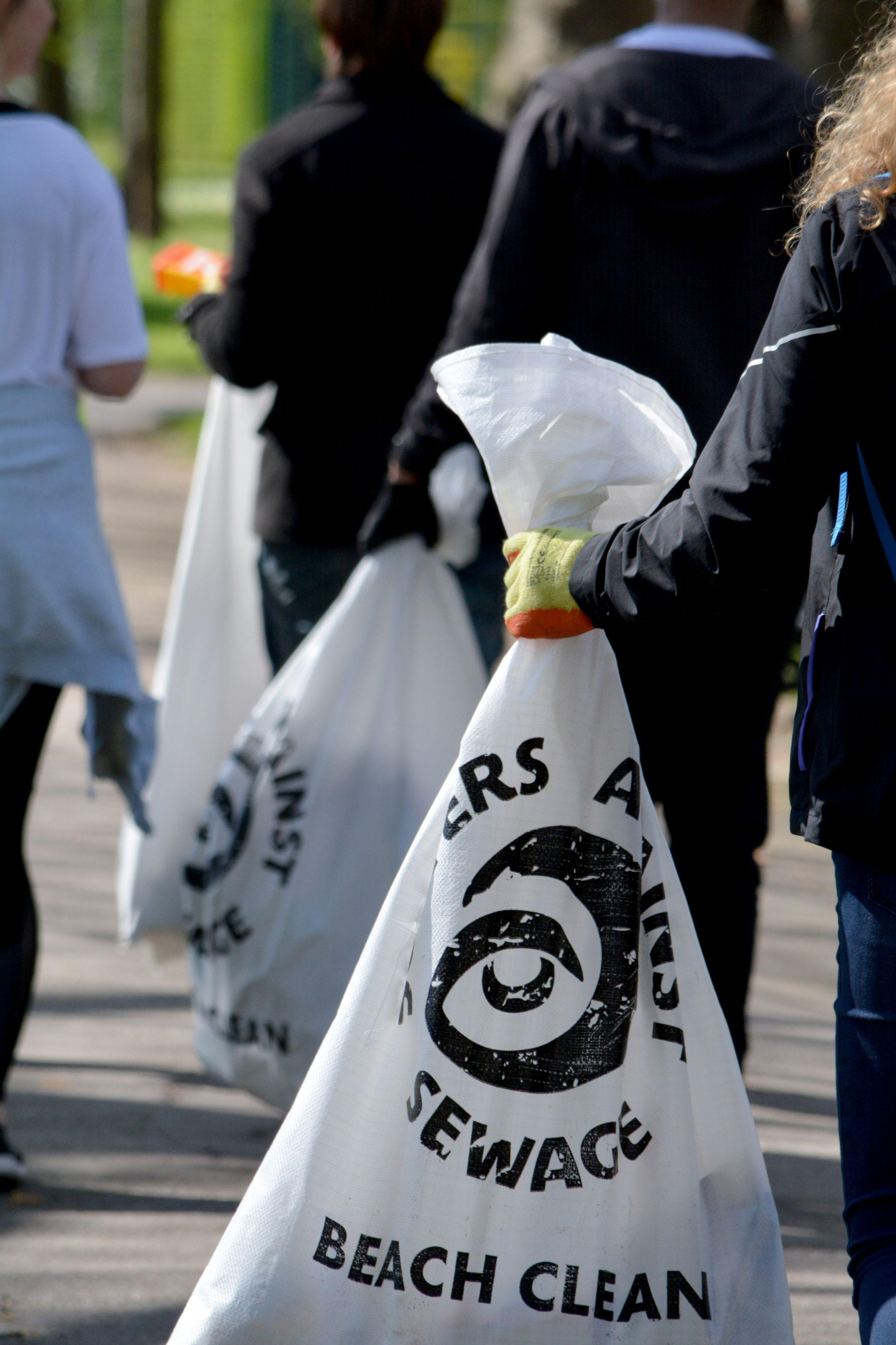 Group of people carrying refuse sacks filled with litter