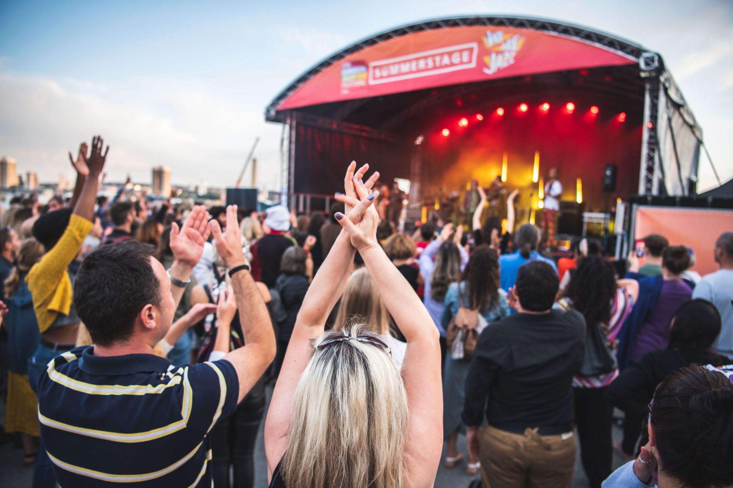 A large crowd watching a band performing on a stage