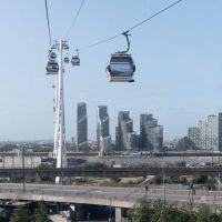 The cable cars flying over the Royal Docks with the Millennium Dome in the background