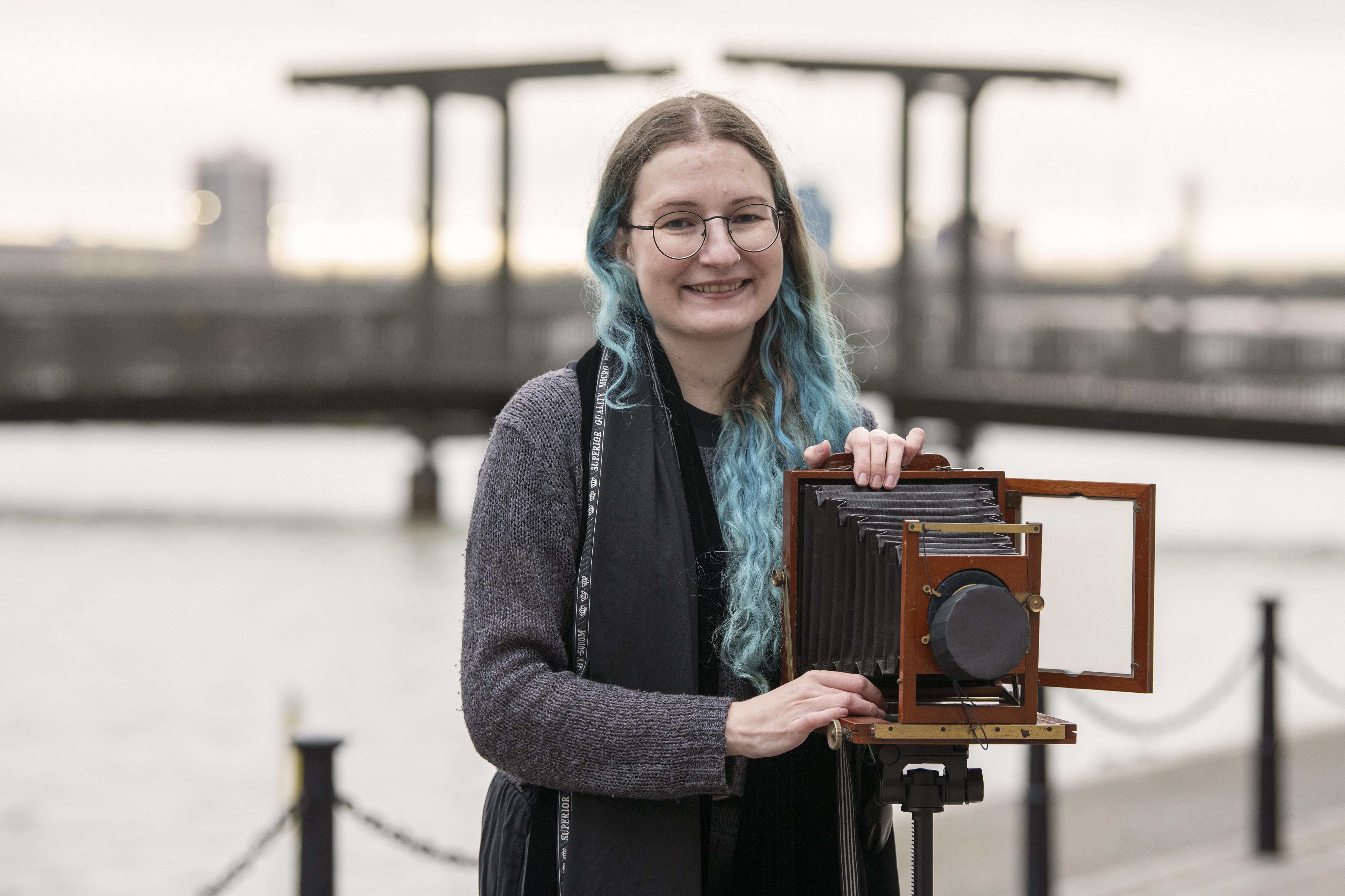 Woman by dock edge with antique camera