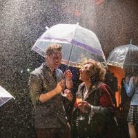 Man and woman under an umbrella in the flavour rainbow, both laughing